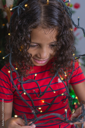 portrait of a beautiful child playing with Christmas lights