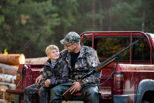 Young hunter boy sit with his father in a truck tailgate © romankosolapov