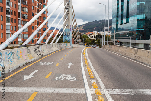BOGOTA, COLOMBIA - A bike way over a vehicular bridge near to a moder building and residential brick buildings