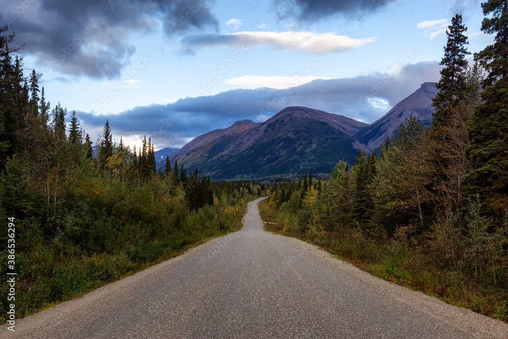 View of Scenic Road surrounded by Trees and Mountains on a Cloudy Fall Morning in Canadian Nature. Taken in Northern British Columbia, Canada.