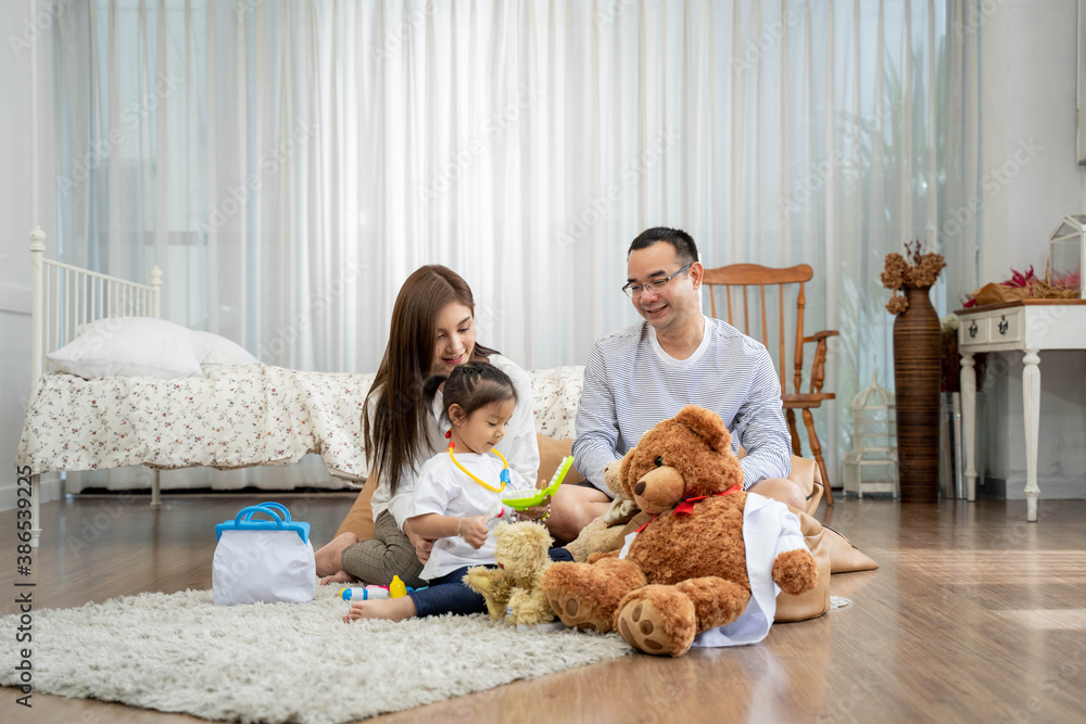 Happy young father and mother and a little daughter playing with Toy, sitting on the floor in living room, family, parenthood and people concept Happy young father and mother and a little daughter playing with Toy, sitting on the floor in living room, family, parenthood and people concept
