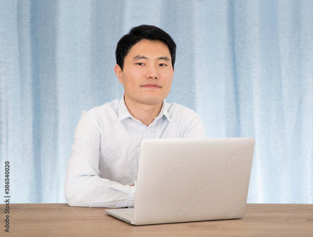 Man sitting in front of curtains working with laptop Man sitting in front of curtains working with laptop