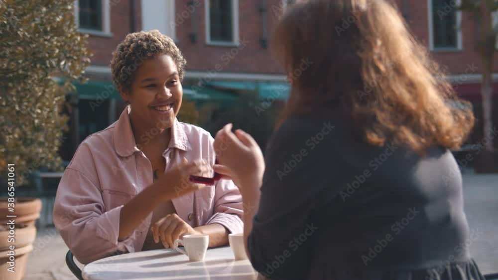 Woman holding engaged ring and making proposal to girlfriend having date in outdoors cafe Woman holding engaged ring and making proposal to girlfriend having date in outdoors cafe