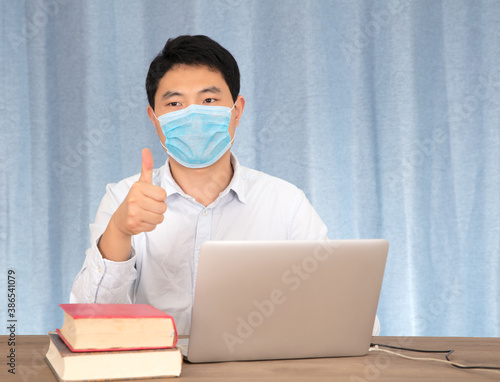 Man with thumbs up wearing mask at desk photo