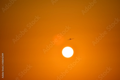The silhouette of the plane on takeoff, with a fiery trace in the tail. It flies during the orange sunset.