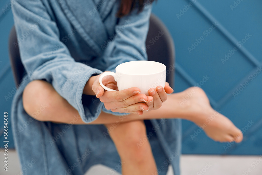 Girl in a studio. Lady in a blue bathrobe. Woman drinking a coffee Girl in a studio. Lady in a blue bathrobe. Woman drinking a coffee