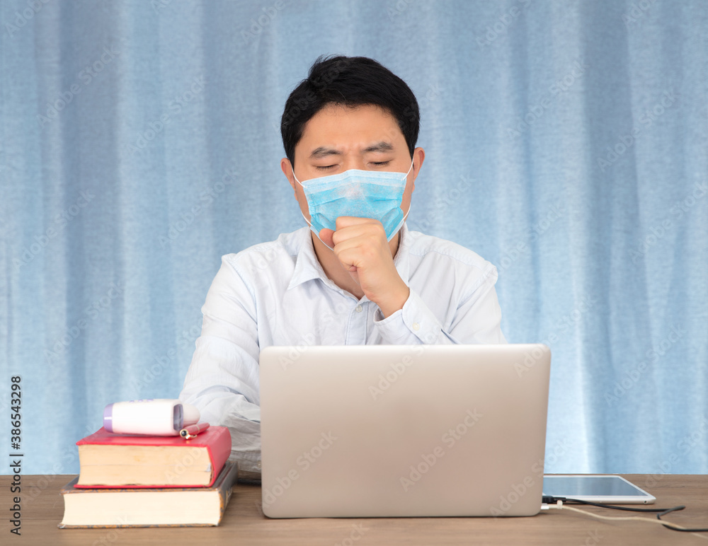 A man wearing a mask at work suddenly coughs A man wearing a mask at work suddenly coughs