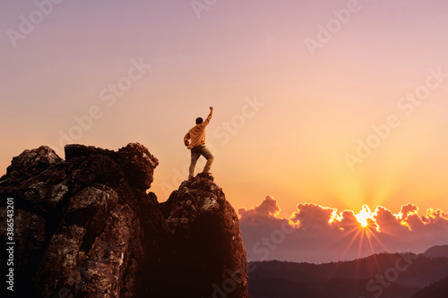 Success male hiker with arms outstretched on top of mountain