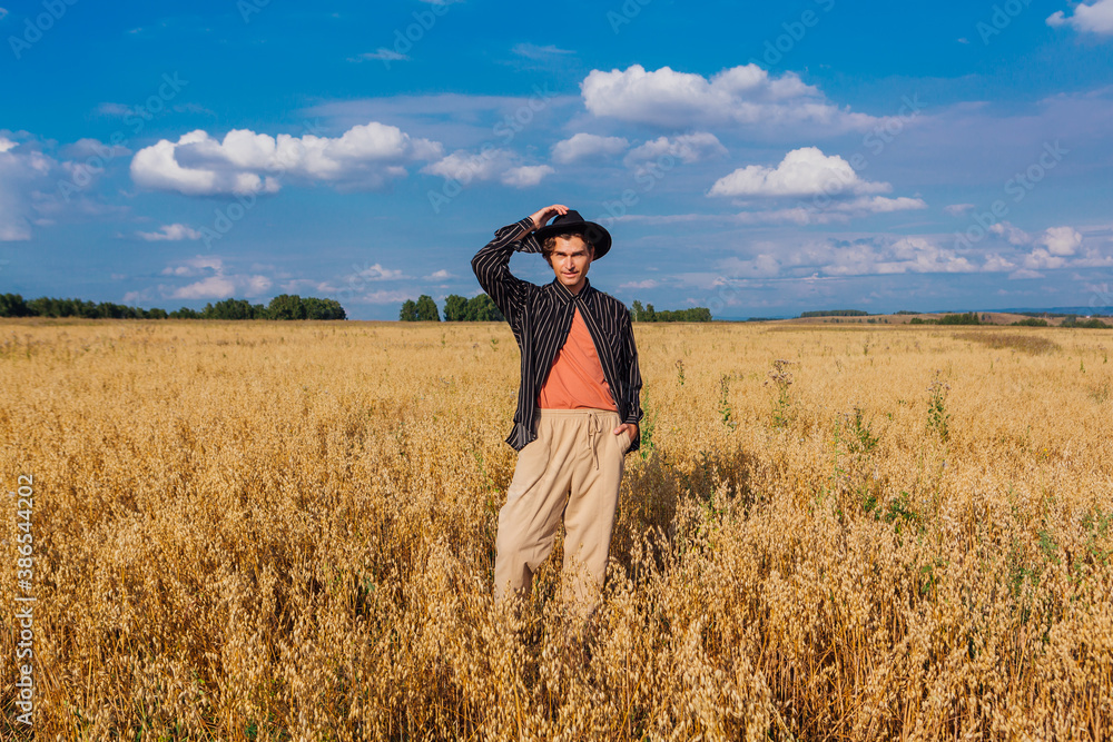 Tall handsome man with black hat standing at golden oat field. Tall handsome man with black hat standing at golden oat field.