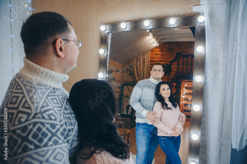 The family celebrates Christmas together. A couple in love hugs in front of the mirror photo