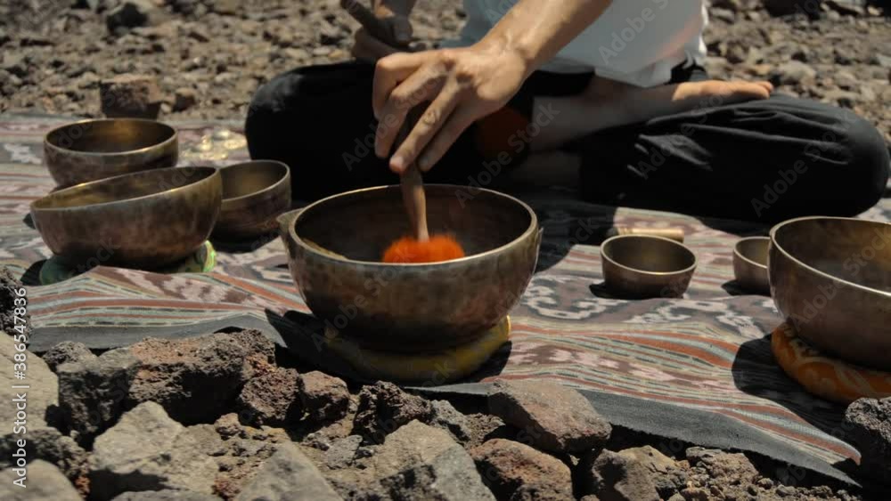 Asian guy playing Tibedt singing copper cups on a viewing mountain Asian guy playing Tibedt singing copper cups on a viewing mountain