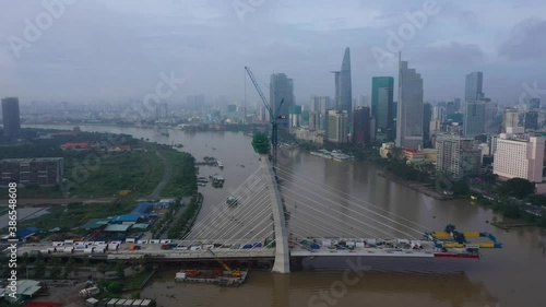 Drone shot of Thu Thiem 2 Bridge is a bridge under construction in Ho Chi Minh City pulling out to reveal city skyline and new development areas. The bridge will span the Saigon River photo