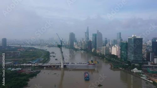 High angle rone shot of Thu Thiem 2 Bridge is a bridge under construction in Ho Chi Minh City with boat carrying shipping containers and city skyline. The bridge will span the Saigon River photo