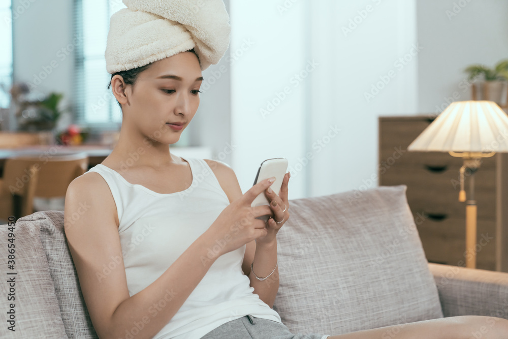 asian woman just having morning shower is using phone on sofa. pretty taiwanese lady wrapping hair with towel is phubbing in relaxed mood. technology and lifestyle. asian woman just having morning shower is using phone on sofa. pretty taiwanese lady wrapping hair with towel is phubbing in relaxed mood. technology and lifestyle.