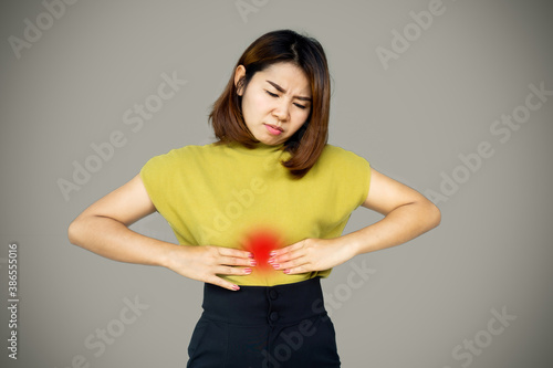 Asian woman suffering from stomach ache, heartburn, abdominal pain photo