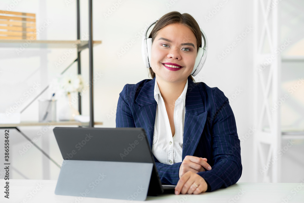 Video conference. Business webinar. Online communication. Virtual corporate meeting. Cheerful confident woman in white headphones working from home office with laptop on light background. Video conference. Business webinar. Online communication. Virtual corporate meeting. Cheerful confident woman in white headphones working from home office with laptop on light background.