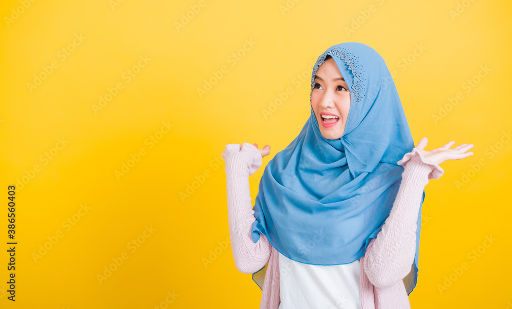 Asian Muslim Arab, Portrait of happy beautiful young woman Islam religious wear veil hijab funny smile she victories expression raises hands glad excited cheerful isolated yellow background Asian Muslim Arab, Portrait of happy beautiful young woman Islam religious wear veil hijab funny smile she victories expression raises hands glad excited cheerful isolated yellow background
