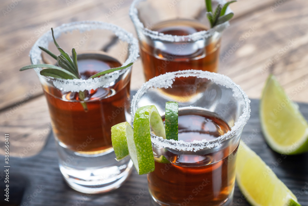 Glass with alcohol, salt and lime on a wooden background. Cognac whiskey tequila. The concept of the party. Selective focus Copy space. Glass with alcohol, salt and lime on a wooden background. Cognac whiskey tequila. The concept of the party. Selective focus Copy space.