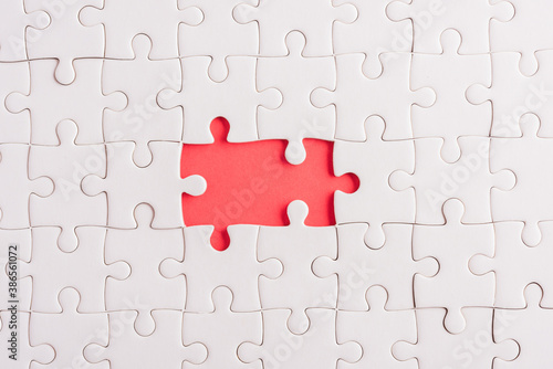 Top view flat lay of paper plain white jigsaw puzzle game texture incomplete or missing piece, studio shot on a red background, quiz calculation concept