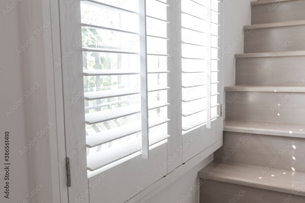 Closeup view of window with horizontal blinds. White Roller Blinds or Louver curtains at the glass window Closeup view of window with horizontal blinds. White Roller Blinds or Louver curtains at the glass window