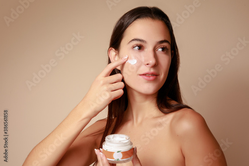 Fototapeta Joven Mujer mexicana aplicando crema humectante facial producto de belleza