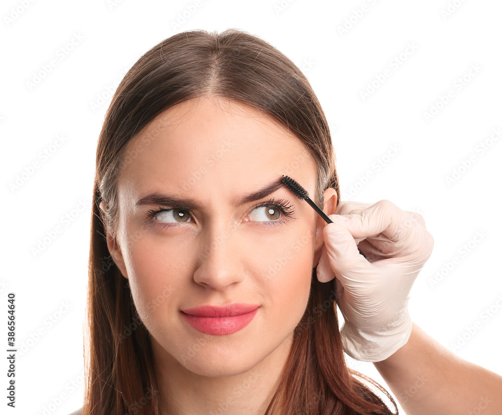 Young woman undergoing eyebrow correction procedure on white background Young woman undergoing eyebrow correction procedure on white background