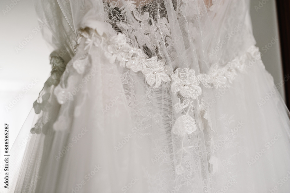 Close-up part of the fashionable beautiful classic lace wedding dress. morning preparation wedding concept. Stylish vintage dress.