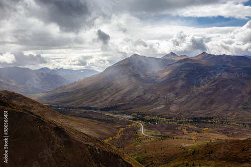 View of Scenic Road from Above surrounded by Trees and Mountains during Fall in Canadian Nature. Aerial Shot. Taken in Tombstone Territorial Park, Yukon, Canada.