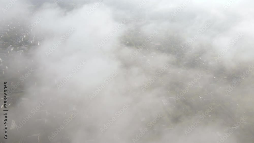 Aerial view on small village in heavy fog. Landscape top view on small summer houses and gardens through the clouds. Drone copter view. Aerial view on small village in heavy fog. Landscape top view on small summer houses and gardens through the clouds. Drone copter view.