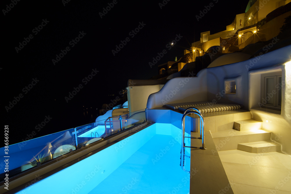 The pool side at night in the romantic village, White hotel at Oia, Santorini, Greece.