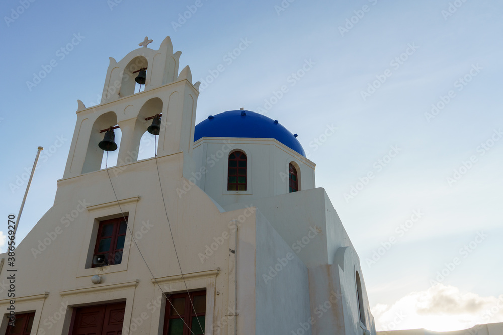 Arch with a bell, white church with blue domes in Oia, Santorini, Greece.