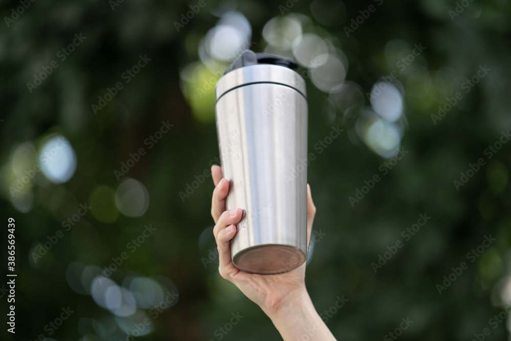 Woman with protein drink in shaker in hand over green background. Woman with protein drink in shaker in hand over green background.