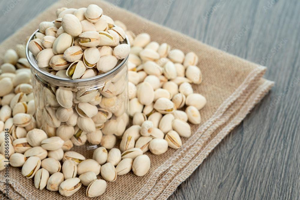 Pistachio nuts in transparent glass jar on a wooden table. Healthy food high protein. Pistachio nuts in transparent glass jar on a wooden table. Healthy food high protein.