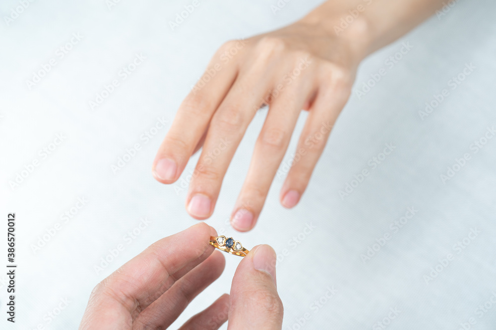 Man putting diamond ring on woman hand over white background.