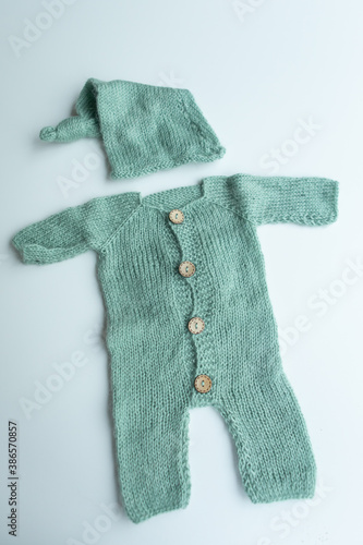 Various colors and types of cotton clothing, knitted newborn clothes and newborn hats on a white background.