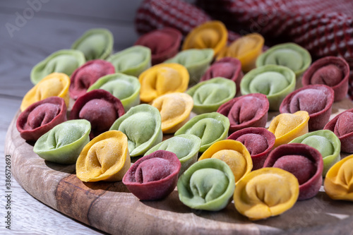 Three color meat dumplings or pelmeni on a wooden board