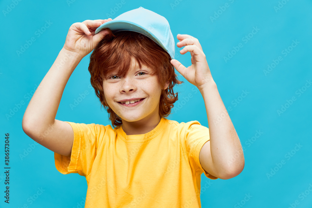 Red-haired boy with a cap on his head smile childhood yellow t-shirt Red-haired boy with a cap on his head smile childhood yellow t-shirt