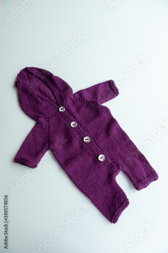 Various colors and types of cotton clothing, knitted newborn clothes and newborn hats on a white background.