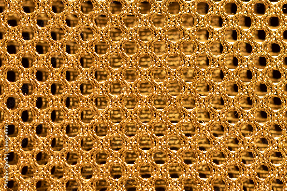Gold double shiny braided metal mesh with a black background behind. Gold double shiny braided metal mesh with a black background behind.