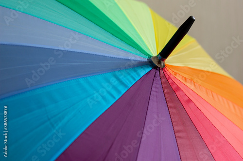 A multi-colored umbrella with stripes in rainbow colors  a symbol of the LGBT flag.