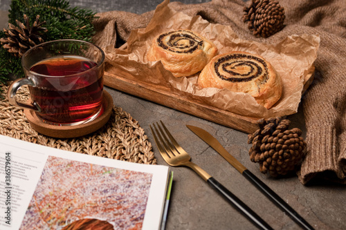 Glass mug with a drink on the table. Baking with poppy seeds. Spruce branch. Side view. Fork spoon. Dessert. Christmas.