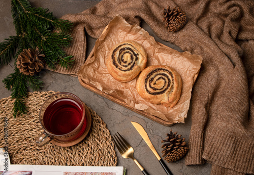 Glass mug with a drink on the table. Baking with poppy seeds. Spruce branch. View from above. Fork. A spoon. Dessert. Pullover. Christmas.