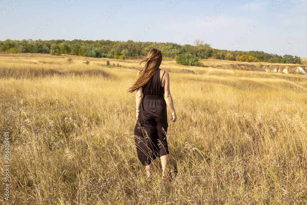 Pretty young dark haired woman in black dress stand in field. Beautiful girl outdoor in the field enjoy with freedom Pretty young dark haired woman in black dress stand in field. Beautiful girl outdoor in the field enjoy with freedom