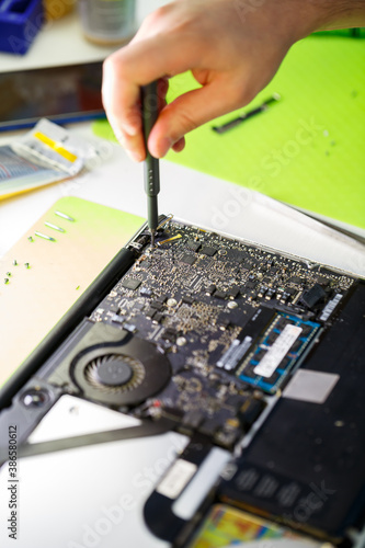 man cleans a laptop with a special tool from dust. Repair and maintenance of laptops and PCs Advertising services for the repair of electronics and devices.