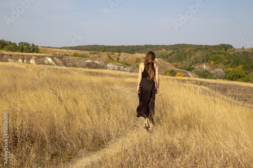Beautiful young dark haired woman in black dress walk in field. Pretty girl  outdoor in the field enjoy with freedom © Olga