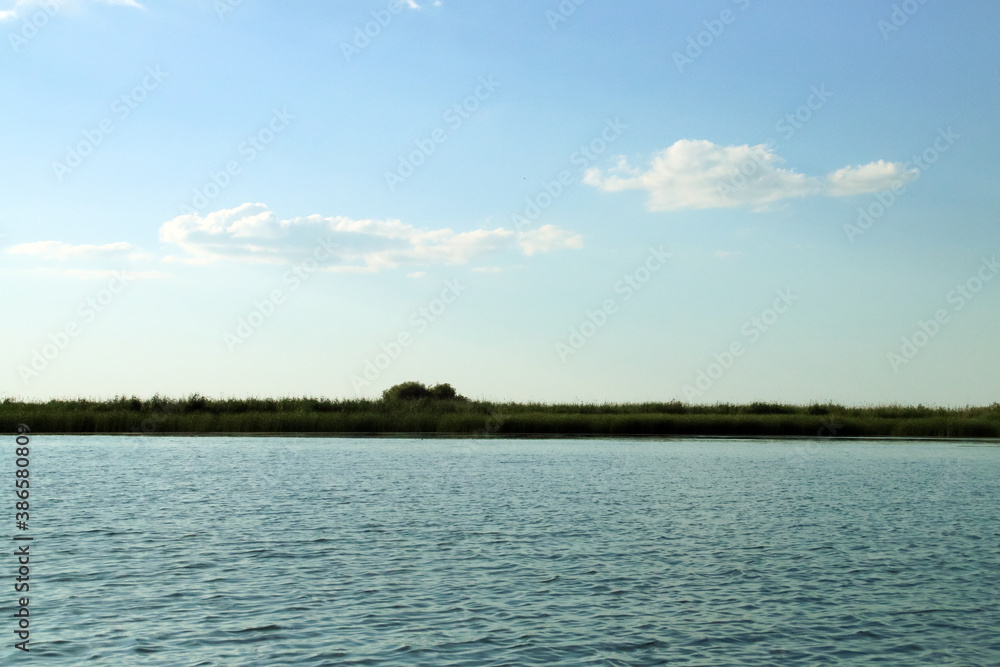 Paisaje del humedal del delta del Danubio en Rumanía. Paisaje compuesto por el agua de la laguna y el cielo, observándose la vegetación acuática en el horizonte . Laguna Gorgova.