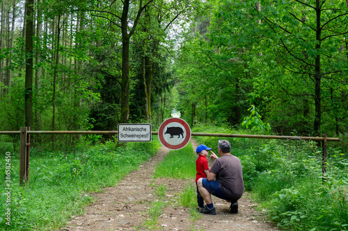 Father and son are standing in the forest on a path that is closed with a barrier. photo