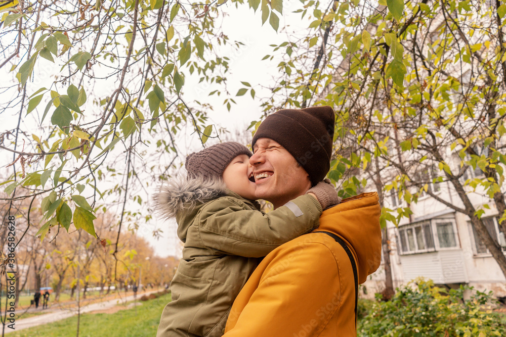 Father have a fun with his little son in a park. Autumn colors, green, orange. Son bites dad in the game. Father have a fun with his little son in a park. Autumn colors, green, orange. Son bites dad in the game.