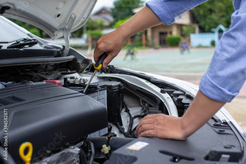 Man's hand is causing his car to crash by using a screwdriver to check various points, car insurance concept.