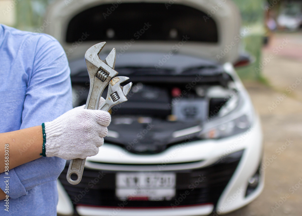 Car repair service, the hand of a car mechanic holding a wrench preparing to repair cars entering the garage. Car repair service, the hand of a car mechanic holding a wrench preparing to repair cars entering the garage.